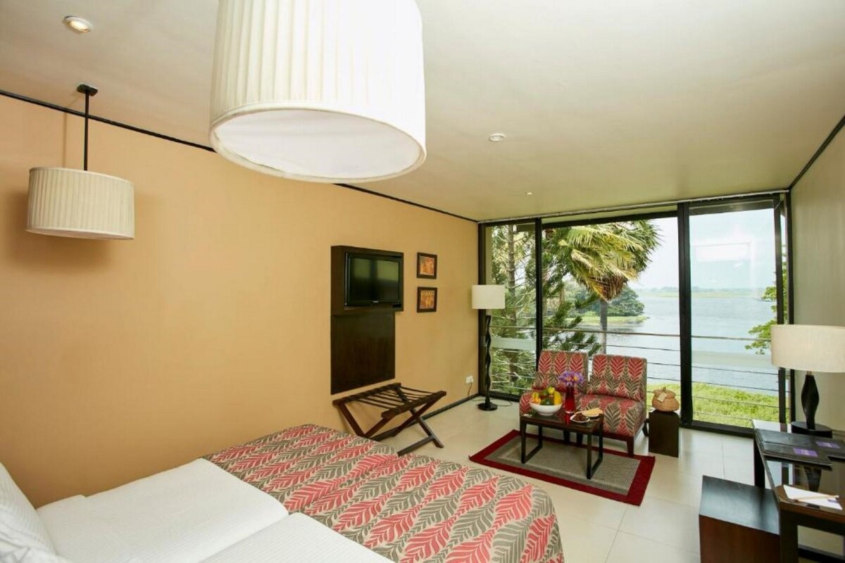 A modern hotel room with a bed, a TV, a desk, and a view of the outdoors.