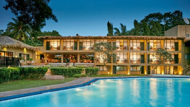 Hotel amb piscina, diversos balcons i estructura de palla.