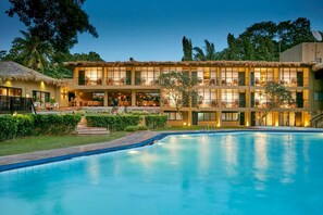A hotel with a swimming pool, multiple balconies, and a thatched-roof structure. - Ekho Safari Tissa Hotel (Thissamaharama)