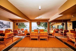 A spacious indoor area with wooden furniture, large windows, and a view of the outdoors. - Ekho Safari Tissa Hotel (Thissamaharama)
