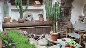Une terrasse rustique agrémentée de cactus en pot, d’un banc en bois et d’une table ornée de fleurs.