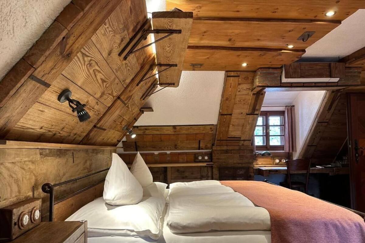 A wooden cabin-style room with a bed, a nightstand, and a dresser.