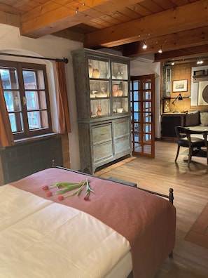 A room with a bed, a cabinet with glass doors, a table, and a chair.