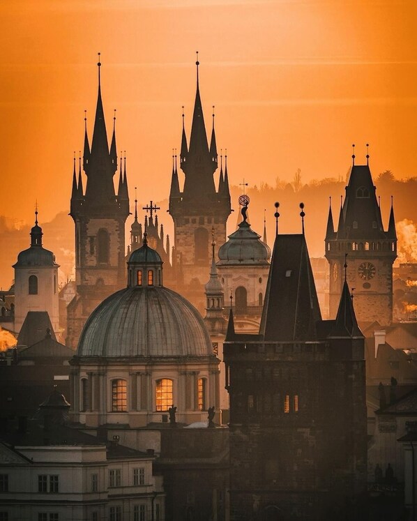 A cityscape with historic buildings, including spires and a dome, during sunset.