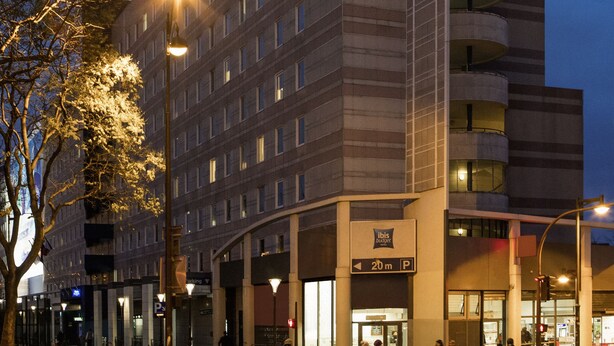 Un hotel con un letrero llamativo, varios pisos y un estacionamiento.