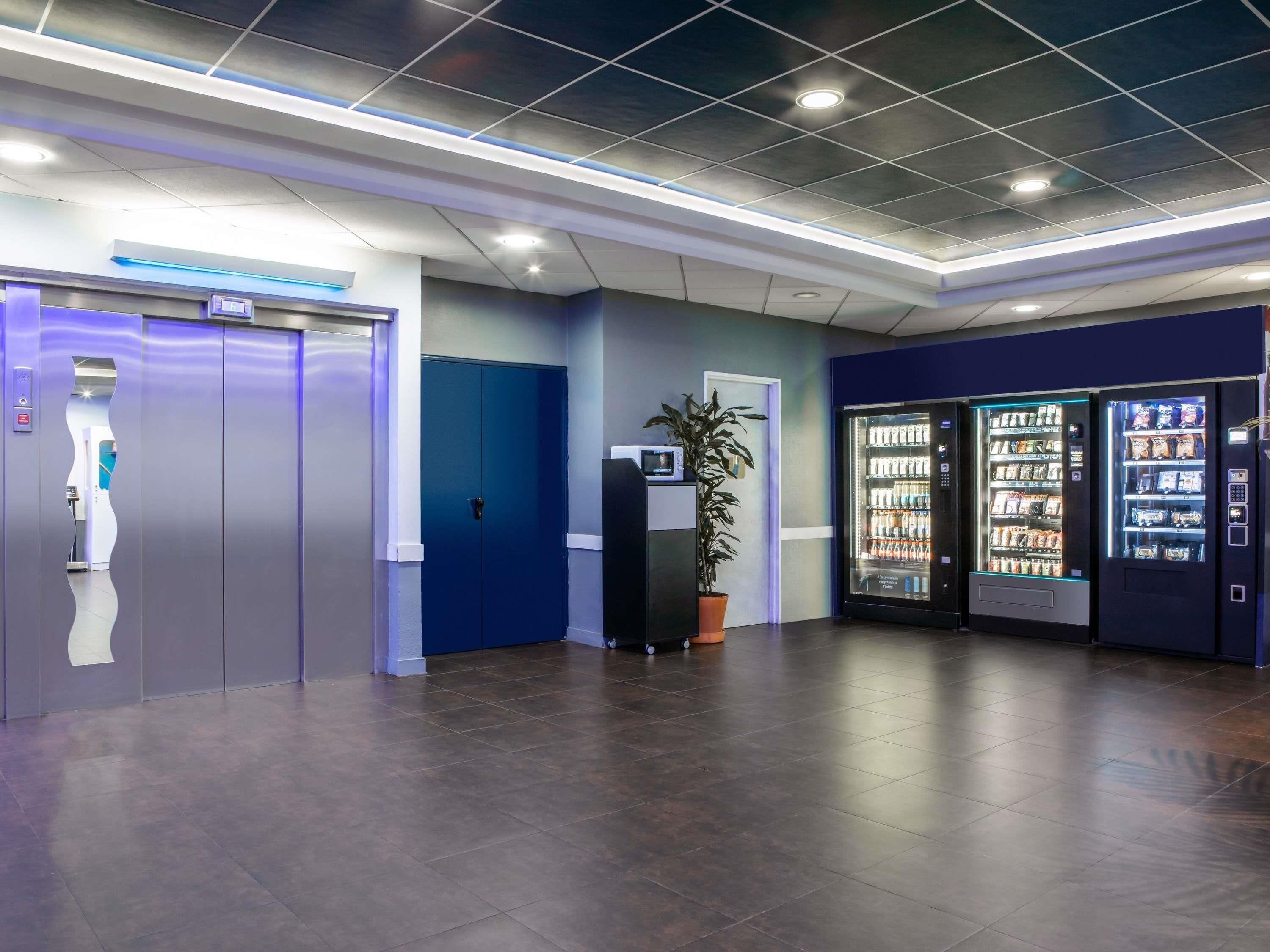 Un hall d’entrée moderne avec un comptoir d’accueil, des distributeurs automatiques et une plante en pot.