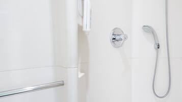 A modern shower with a handheld showerhead and a wall-mounted faucet.