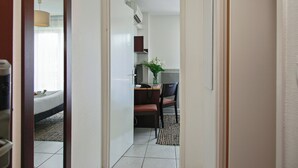 A hotel room with a bed, a desk with a chair, a small table with a vase of flowers, and a window with curtains. - Park & Suites Toulouse Colomiers (Toulouse)