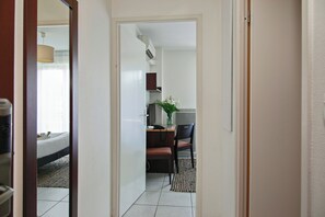 Een hotelkamer met een bed, een bureau met stoel, een tafeltje met een bloemenvaas en een raam met gordijnen.