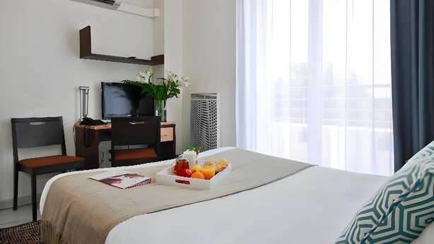 A hotel room with a bed, a desk with a computer, a chair, a TV, and a window with curtains. - Park & Suites Toulouse Colomiers (Toulouse)