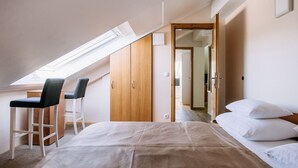Un dormitorio con cama, escritorio, sillas, tragaluz y armario de madera.
