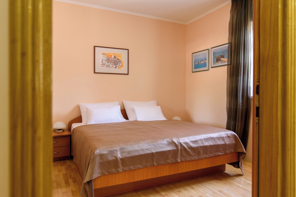 Quarto com cama de madeira, mesa de cabeceira e luminária na parede.