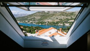 Vista a través de una ventana que muestra una montaña y una masa de agua al fondo.