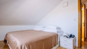Un dormitorio con cama, mesita de noche blanca y puerta de madera.