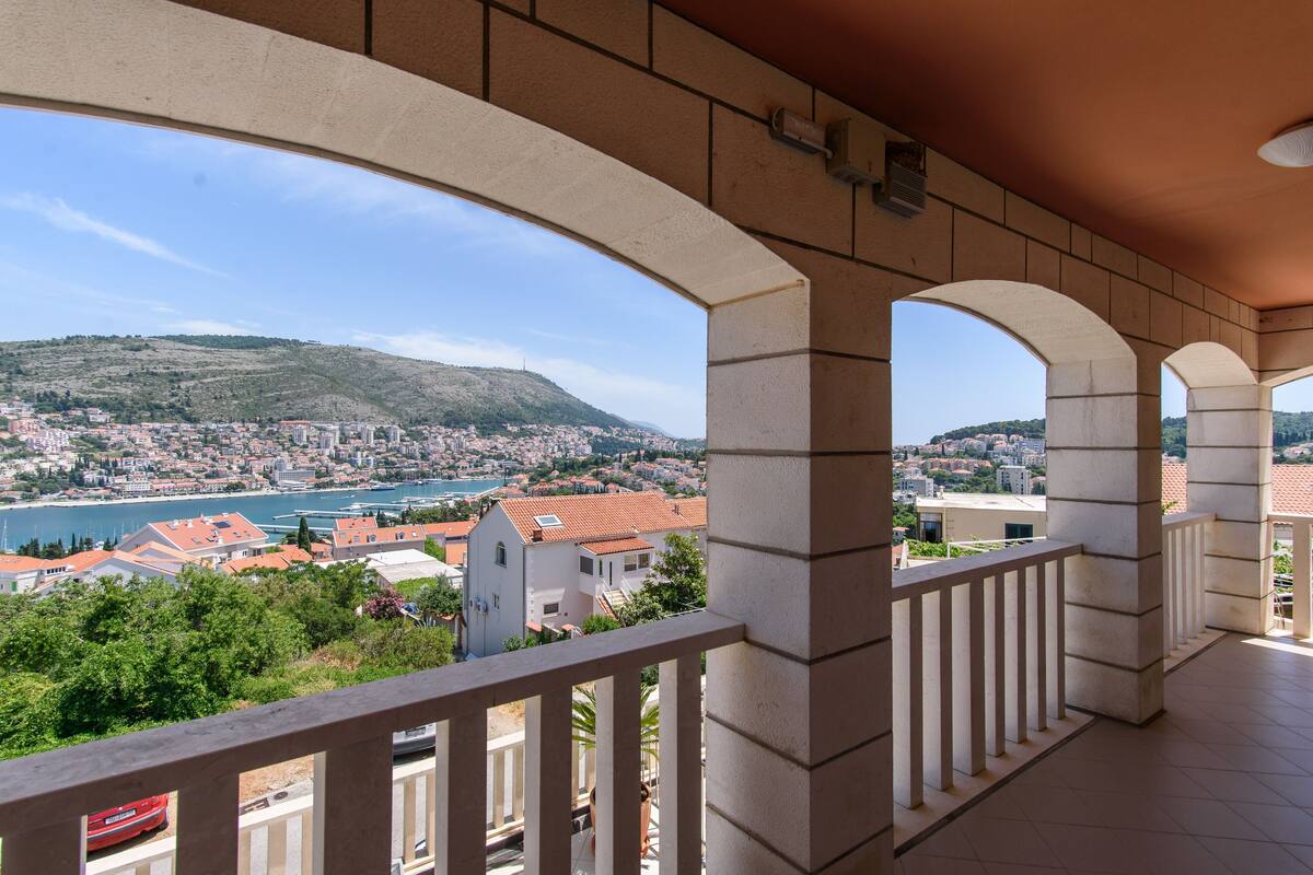 Varanda com vista para a paisagem costeira, incluindo uma colina e um corpo de água.