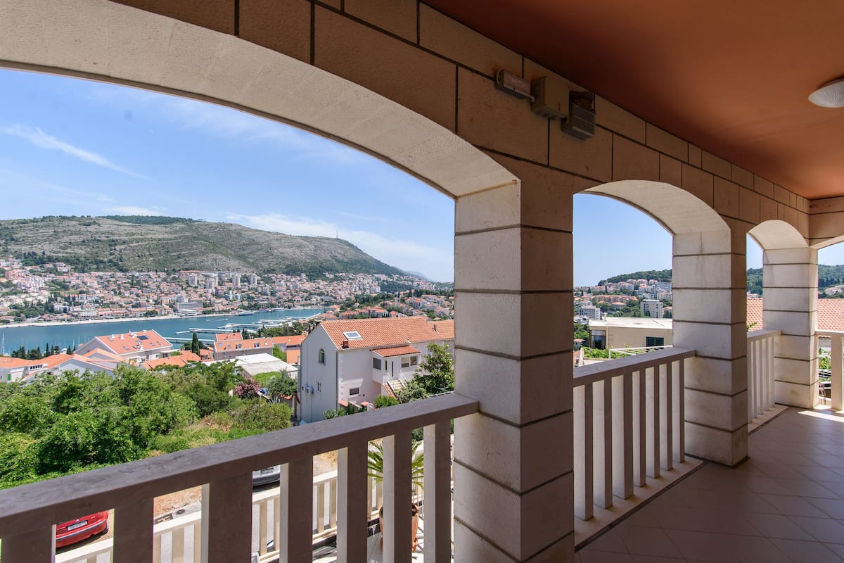 Varanda com vista para a paisagem costeira, incluindo uma colina e um corpo de água.