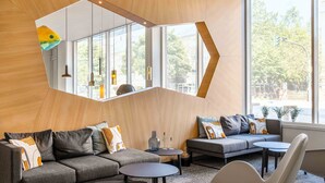 Una sala de estar moderna con un sofá, sillones y una mesa de centro. Amplias ventanas ofrecen luz natural y vistas al exterior.