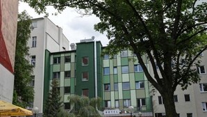 Ein Hotel mit grüner Fassade, zahlreichen Fenstern und einem Schild, das es als Hotel kennzeichnet.