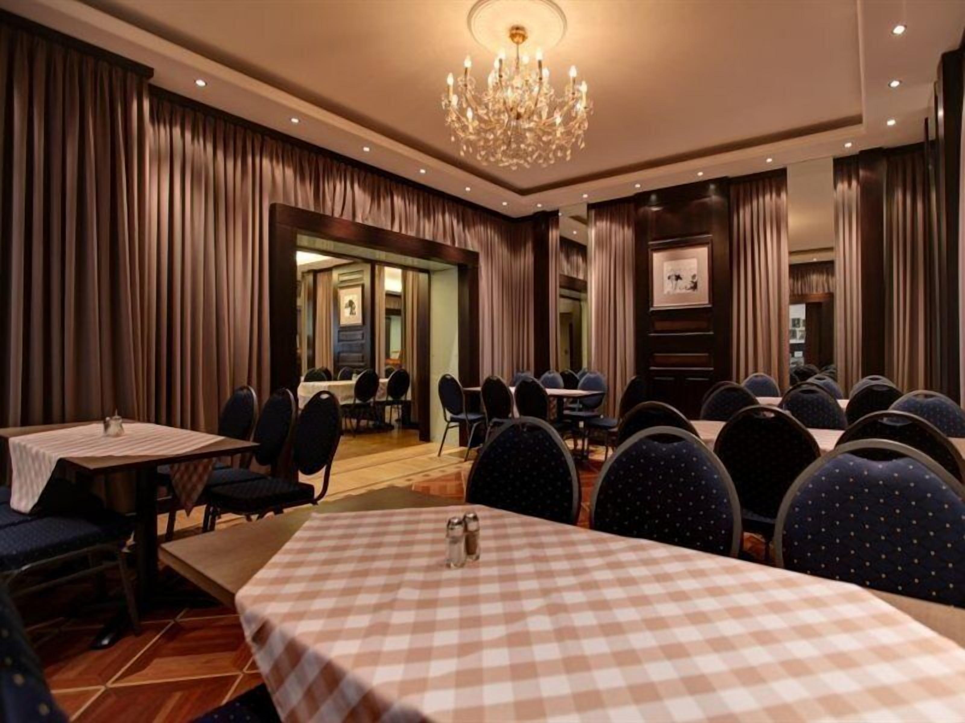 Ein Hotelrestaurant mit karierten Tischdecken, runden Tischen und Stühlen.