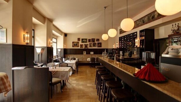 Ein Restaurant mit Barbereich, Holzboden und Pendelleuchten.