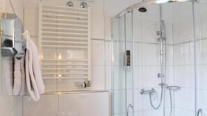 Ein modernes Badezimmer mit einer gläsernen Duschkabine, einem Handtuchhalter und einer integrierten Heizung.