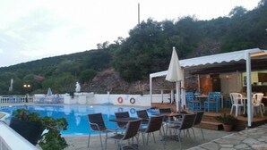 A poolside area with a seating arrangement and a covered outdoor dining area.
