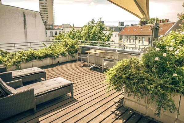 Terraço no telhado com mobiliário de vime, uma mesa e cadeiras.