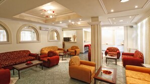 A spacious living area with multiple sofas and armchairs, a coffee table, and a television. - Hotel Galaxias (Corfu)
