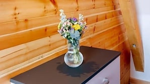 Una parete di legno con un lampadario e un vaso di fiori su un mobiletto.