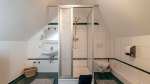 Une salle de bain équipée d’une douche, de toilettes, d’un lavabo et d’un porte-serviettes.