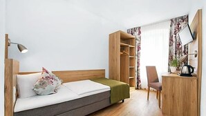 Una camera compatta con un letto, una scrivania, una sedia, un armadio e una TV.