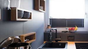 A modern kitchen with a built-in stove, a sink, and a window with blinds. - Das Nordberg Guesthouse (Garmisch-Partenkirchen)