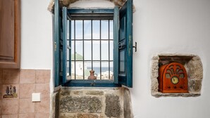 A stone doorway with a blue door, a small window with a radio, and a tiled wall with a light switch. - Venetiko Apartments (Naxos)