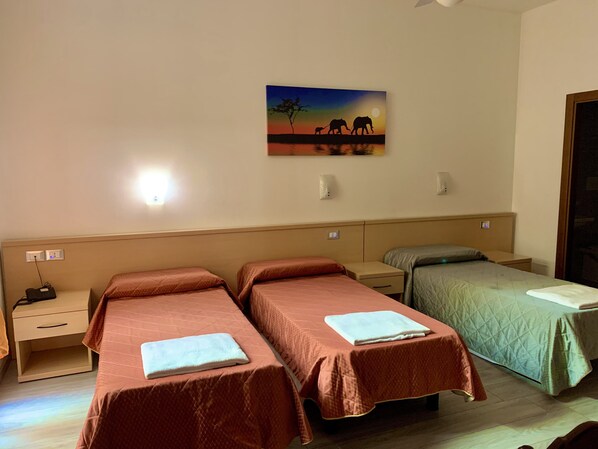 Habitación de hotel con dos camas individuales, una mesita de noche y un cuadro colgado en la pared con elefantes.