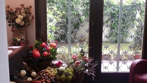A room with a wooden floor, a red chair, and a window with a metal gate. - Casa Calicantus (Milan)
