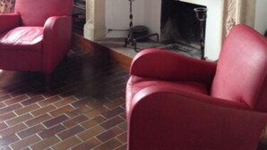 A room with a fireplace, two red armchairs, and a brick floor. - Casa Calicantus (Milan)