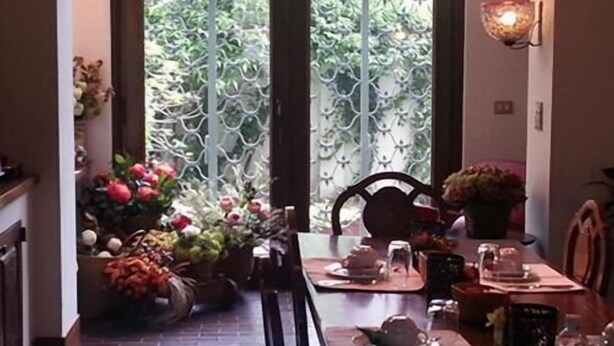A dining area with a long table, chairs, and a vase of flowers. - Casa Calicantus (Milan)