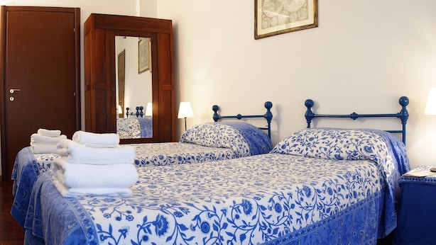 A bedroom with two beds, a wooden door, a mirror, and a bedside table with a lamp. - 2 Passi Da (Rome)