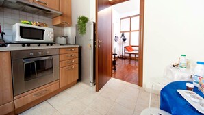 A kitchen with stainless steel appliances, wooden cabinets, and a tiled floor. - 2 Passi Da (Rome)
