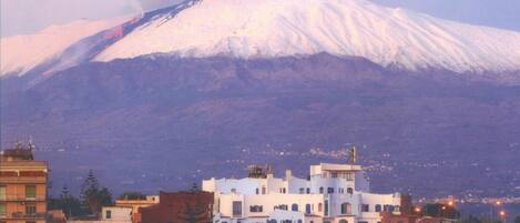 A snow-capped mountain with a town in the foreground featuring multi-story buildings with balconies.