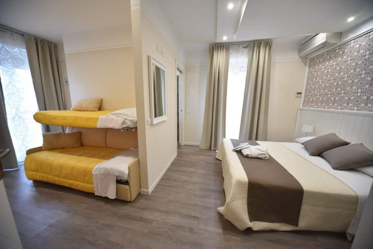 A hotel room with a bunk bed, a single bed, and a shower area.