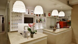 A modern reception area with a counter, potted orchids, and a coffee machine. - Villa Edda (Riccione)
