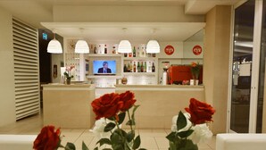 A hotel lobby with a reception desk, a television, and a bar area. - Villa Edda (Riccione)