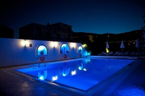 A swimming pool with illuminated arches and lounge chairs.