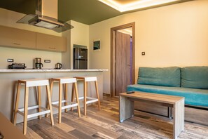 A modern kitchen with a built-in stove, bar stools, and a coffee machine. - Bright Star (Rhodes)