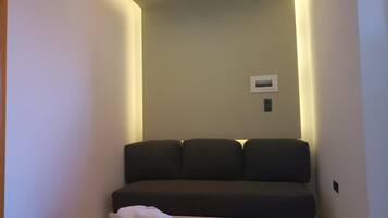 Una sala de estar moderna con un sofá, una mesita y un aire acondicionado instalado en la pared.