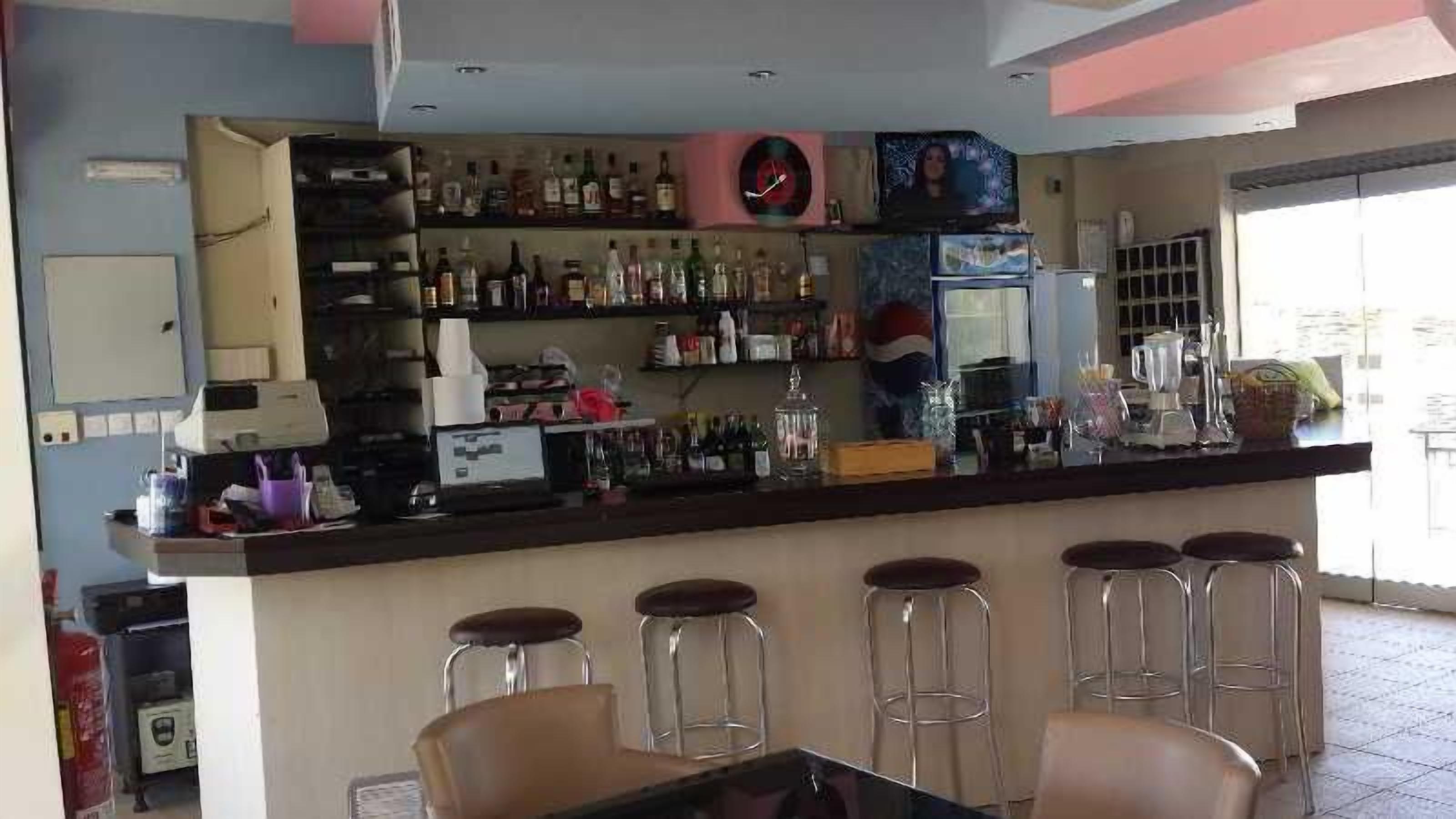 Un espace bar avec des tabourets, un comptoir avec des bouteilles et un téléviseur.