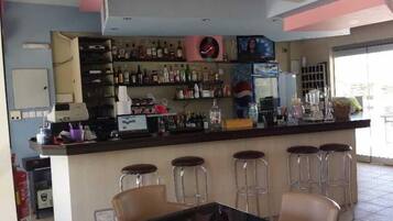 Un espace bar avec des tabourets, un comptoir avec des bouteilles et un téléviseur.