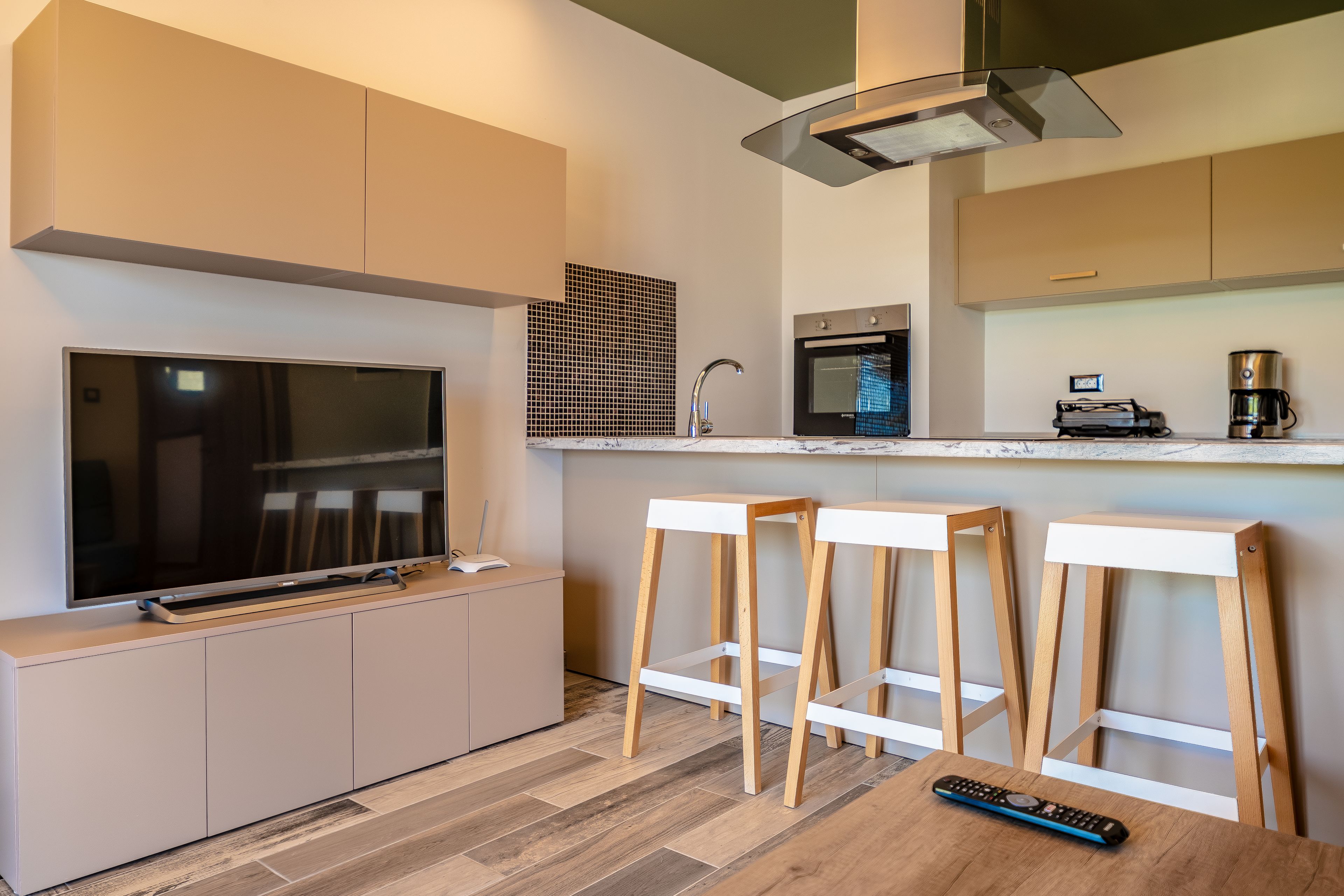 A modern kitchen with a built-in oven, a coffee maker, and a television on a cabinet. - Bright Star (Rhodes)