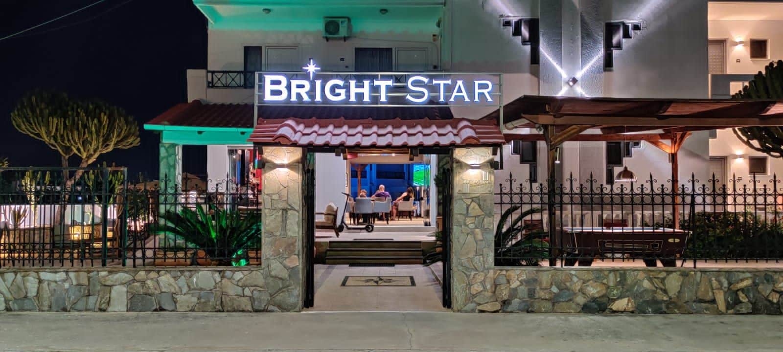 Entrada de hotel con un letrero que dice 'BRIGHT STAR', paredes de piedra y una valla metálica.